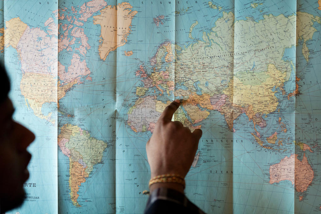 An asylum seeker shows his refugee route from his home country to Switzerland on a world map.