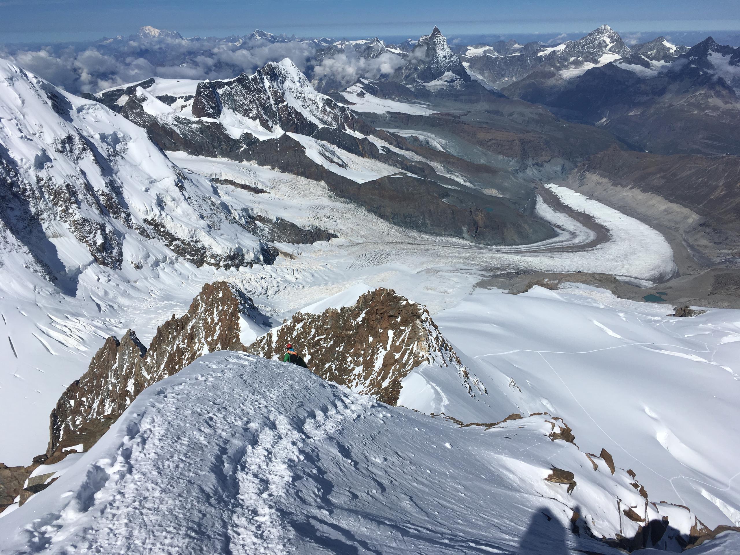 From a mountaintop, one sees Mont Blanc and the Matterhorn in the distance