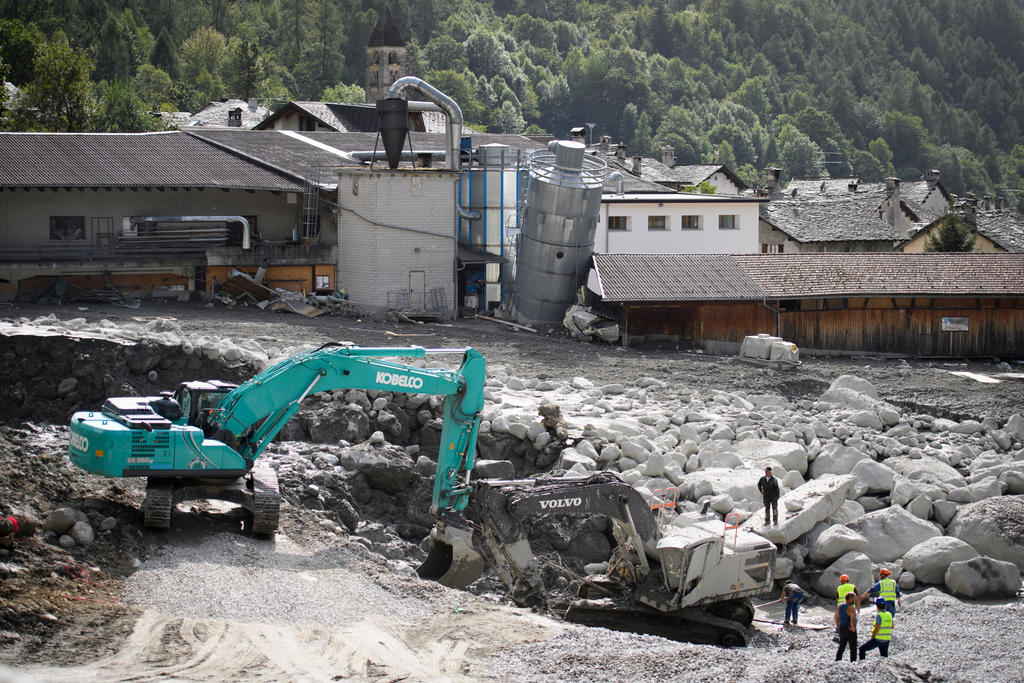 A bulldozer clears a basin of rock from a landslide