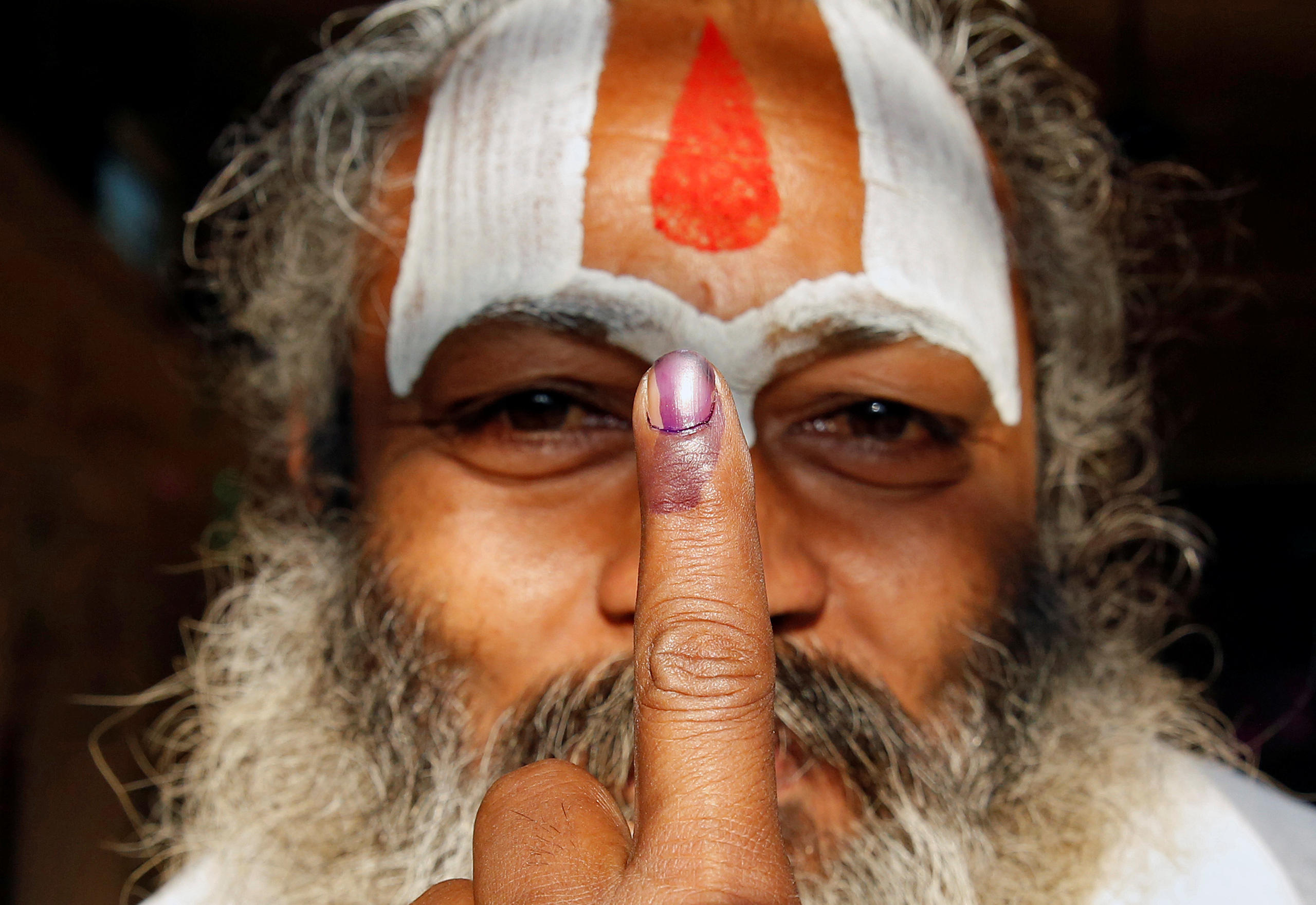 Monje indú muestra dedo entintado tras votar en parlamentarias en Uttar Pradesch, India.