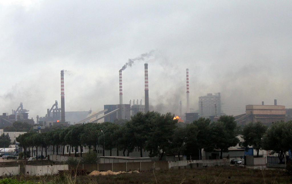 A large factory belches smoke into the air over a town
