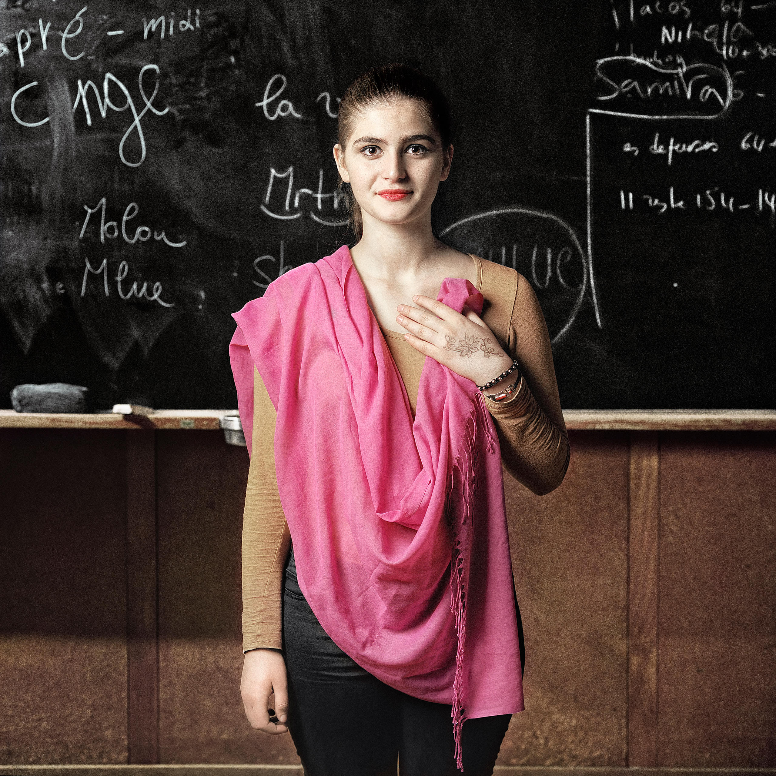 teenager stands in front of blackboard holding a pink shawl