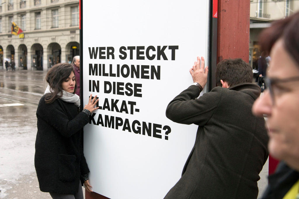 Надпись: «Кто инвестирует миллионы в эту плакатную кампанию»?