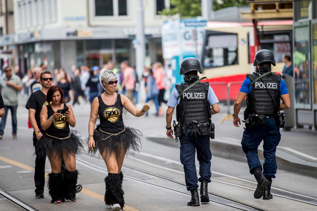 チューリヒのストリート・パレードで通りを歩く参加者と警察官