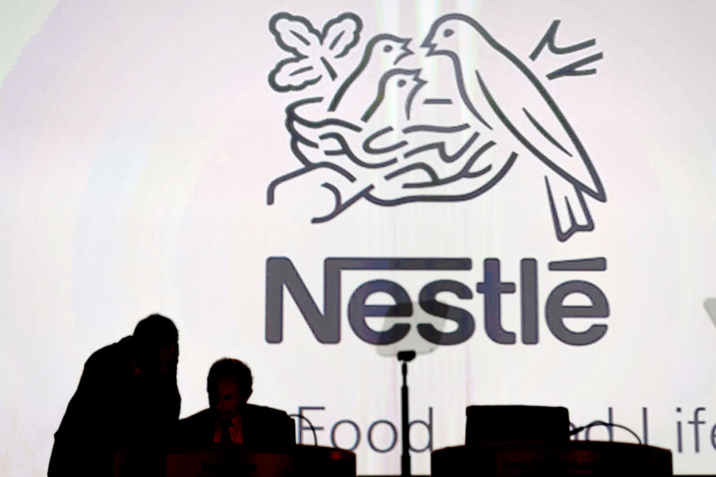 Nestle s directors speak in front of the Nestle s logo