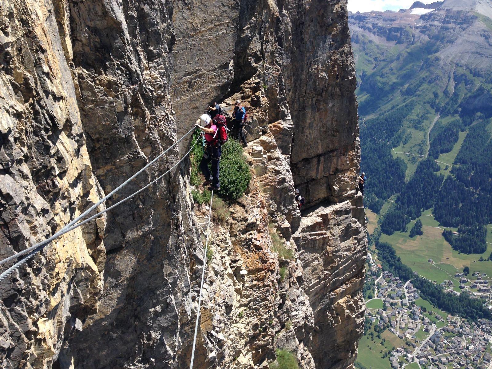 The author follows a via ferrata cable along a sheer mountain face