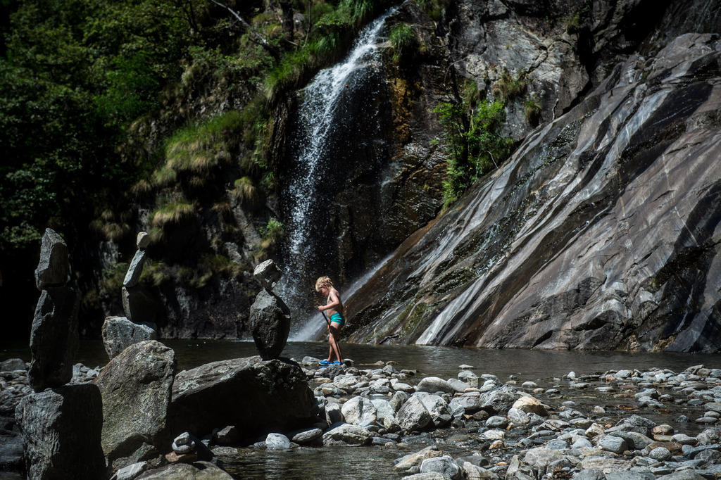 Bambino che passeggia tra i sassi di un fiume