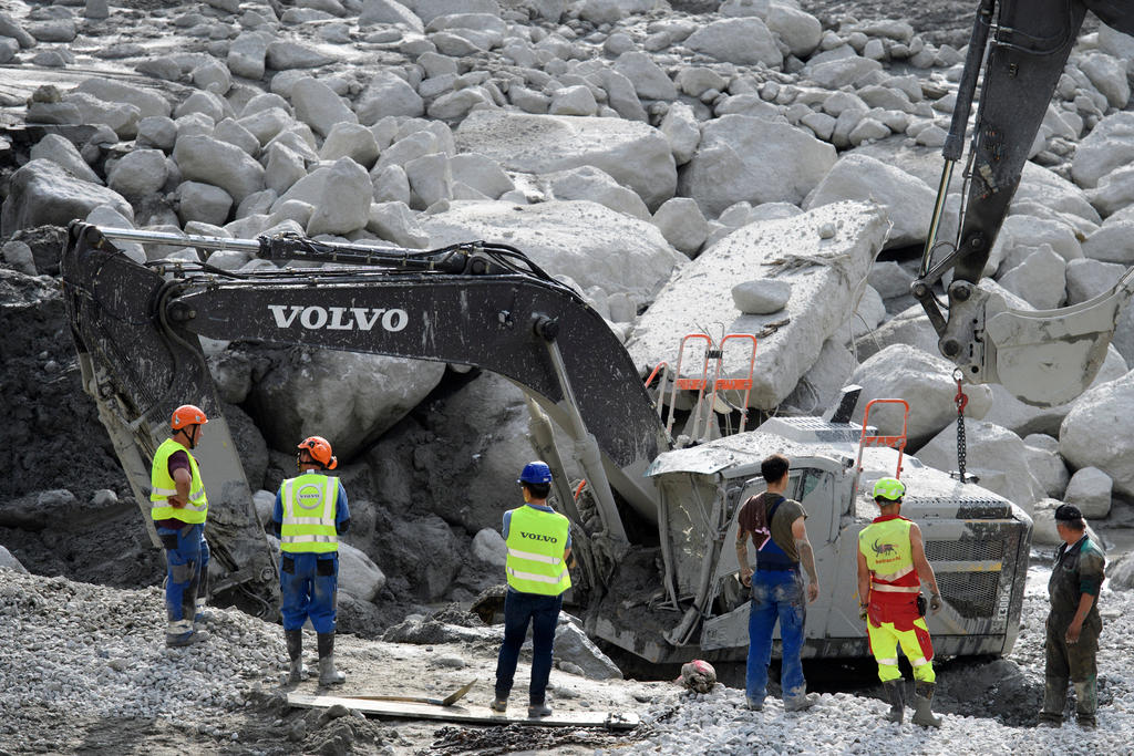 workers clean rocks from the swiss village of Bondo, after a landslide