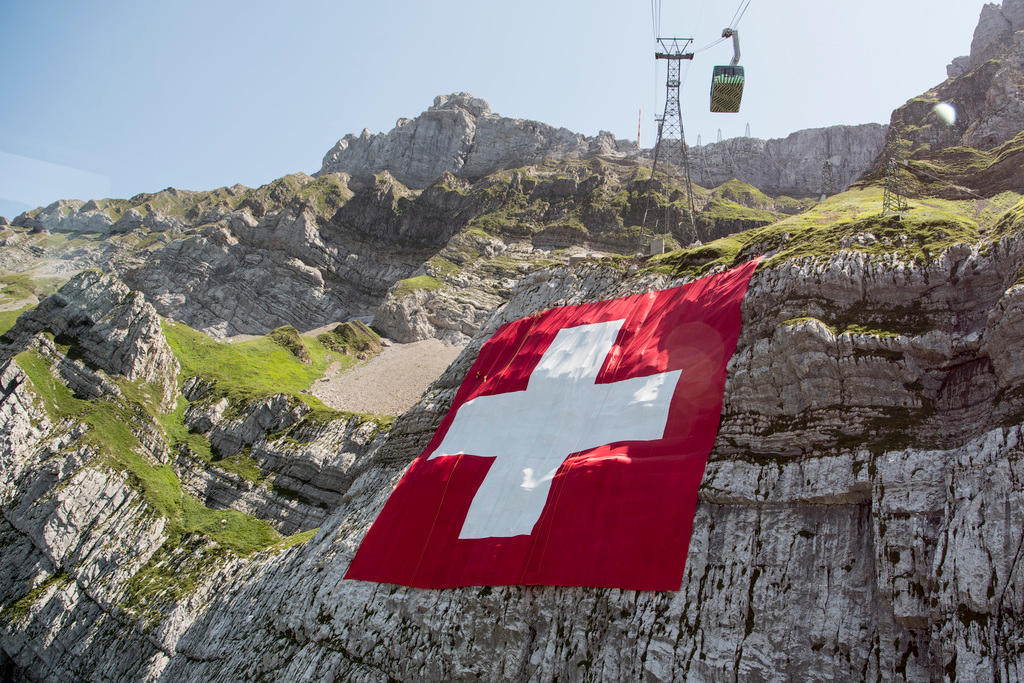 Una bandiera svizzera gigante è adagiata sopra una roccia.