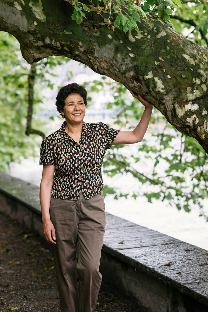 Eine Frau stützt sich an einen Baum und lächelt