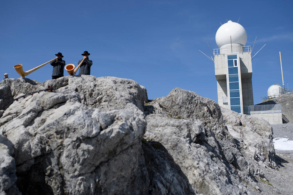 Alphorn players perform in front of the newest radar station for the Swiss weather service on September 8