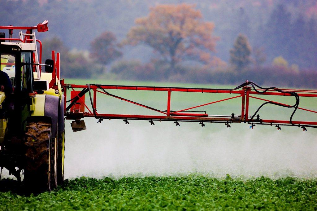 un trattore spande pesticidi su un campo