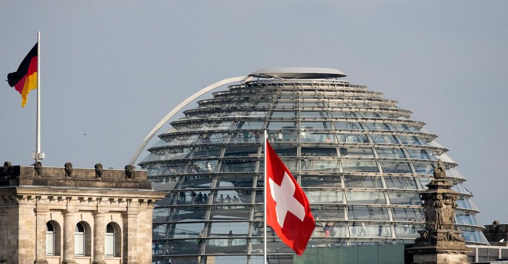 A Swiss flag on the roof of the embassy of Switzerland flies in front of the Reichstag building in Berlin.