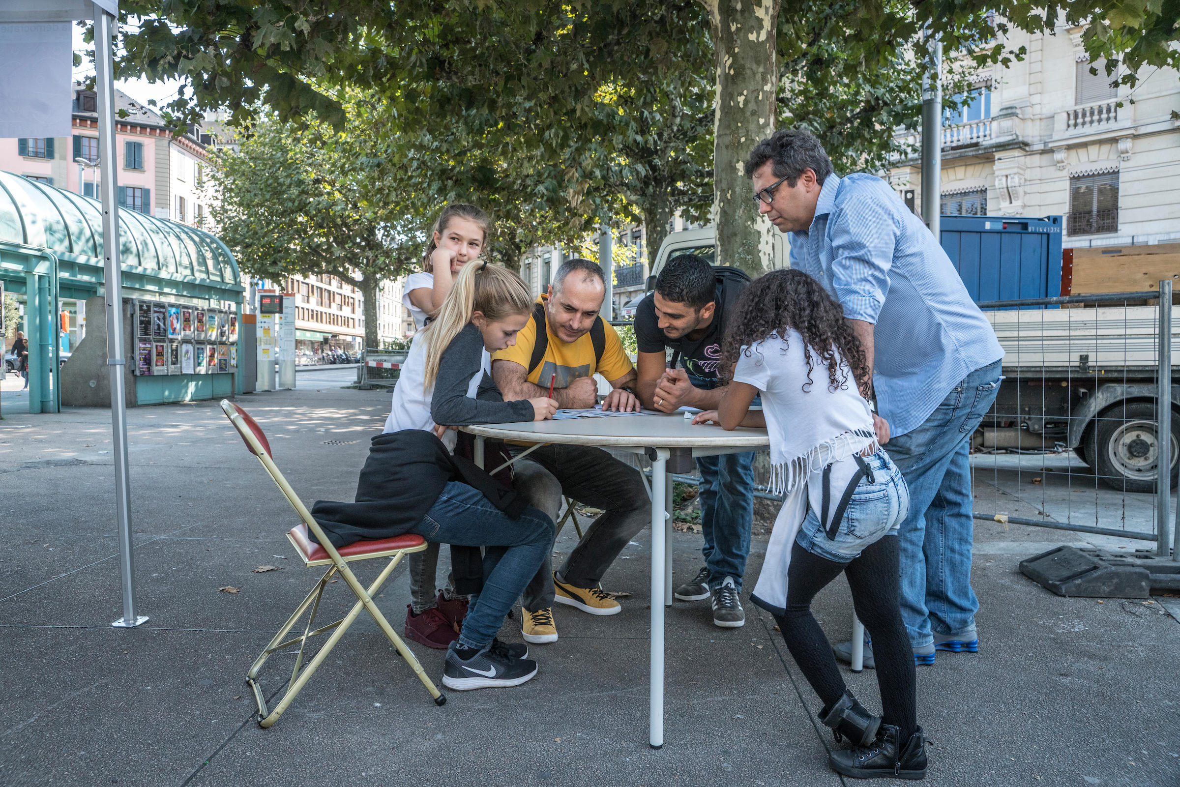 Team of six people sitting and standing around a table in the streets of Geneva