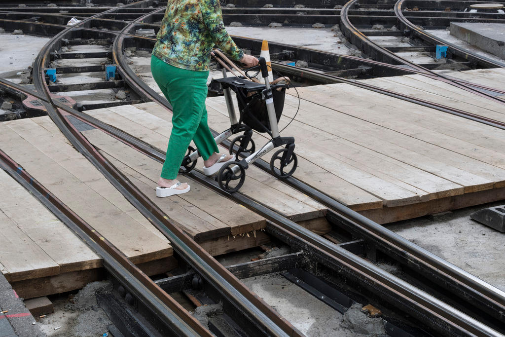 Elderly woman with walking frame crossing rail tracks
