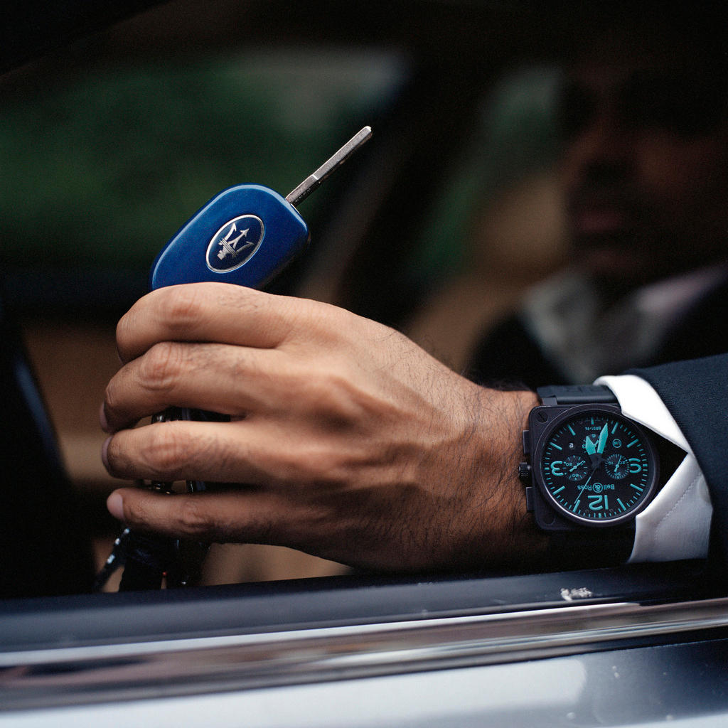 A man s hand, with watch on wrist, holds a car key
