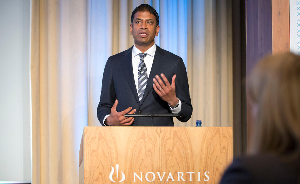 Novartis chief Vasant Narasimhan speaks at a podium.