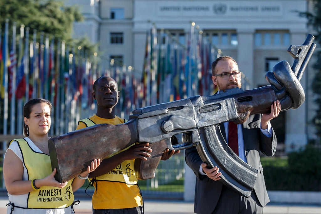 Amnesty International activists hold a giant gun replica AK-47 during a rally