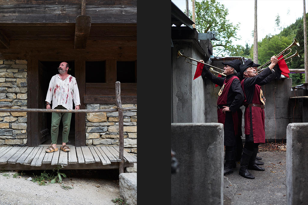 A man in blood stained clothing outside a hut as men in robes play wind instruments