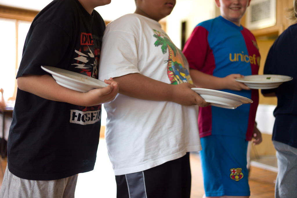 three overweight boys holding plates