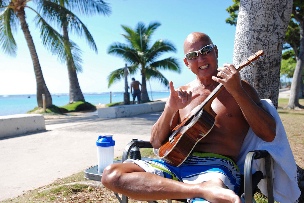 Un hombre en la playa toca la guitarra.
