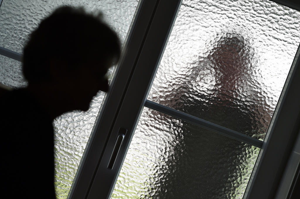 Assediador observa uma mulher através de uma vidraça