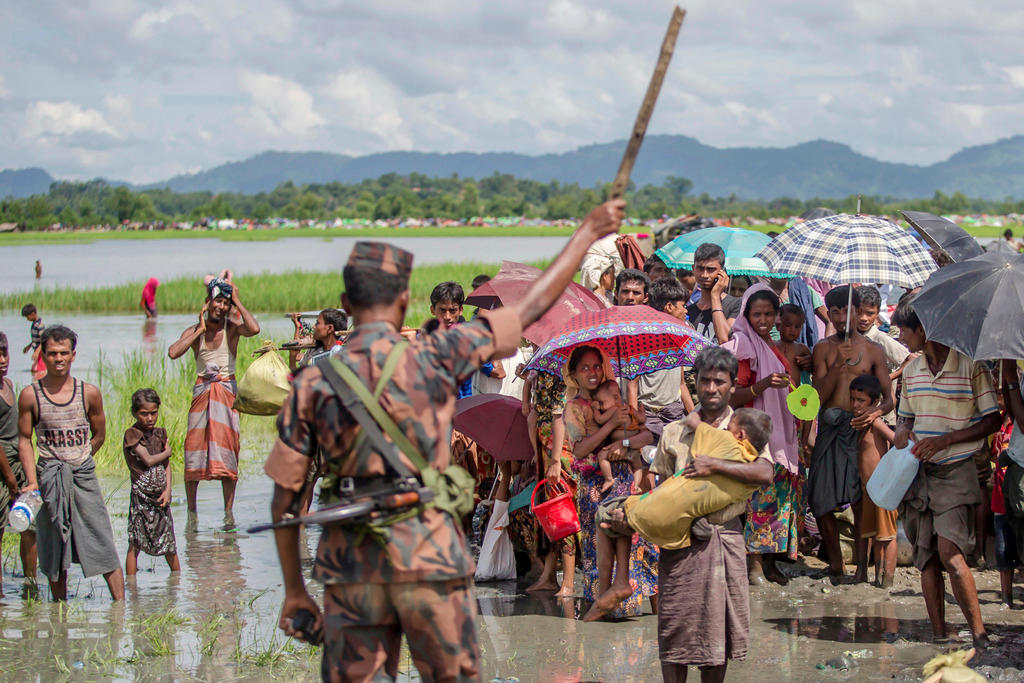 A soldier waves a stick in front of civilians in Myanmar