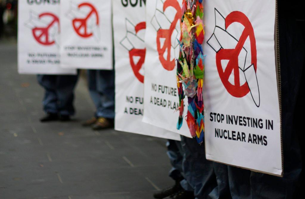 People carrying signs saying: Stop Investing in Nuclear Arms