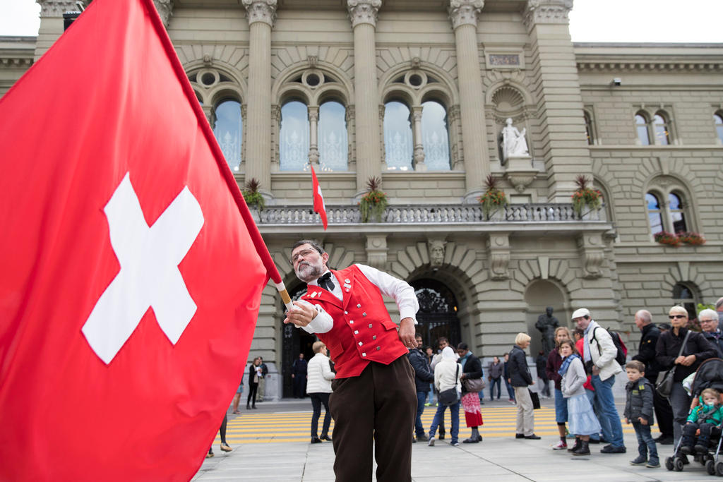 Homem com uma bandeira suíça frente ao Palácio Federal em Berna