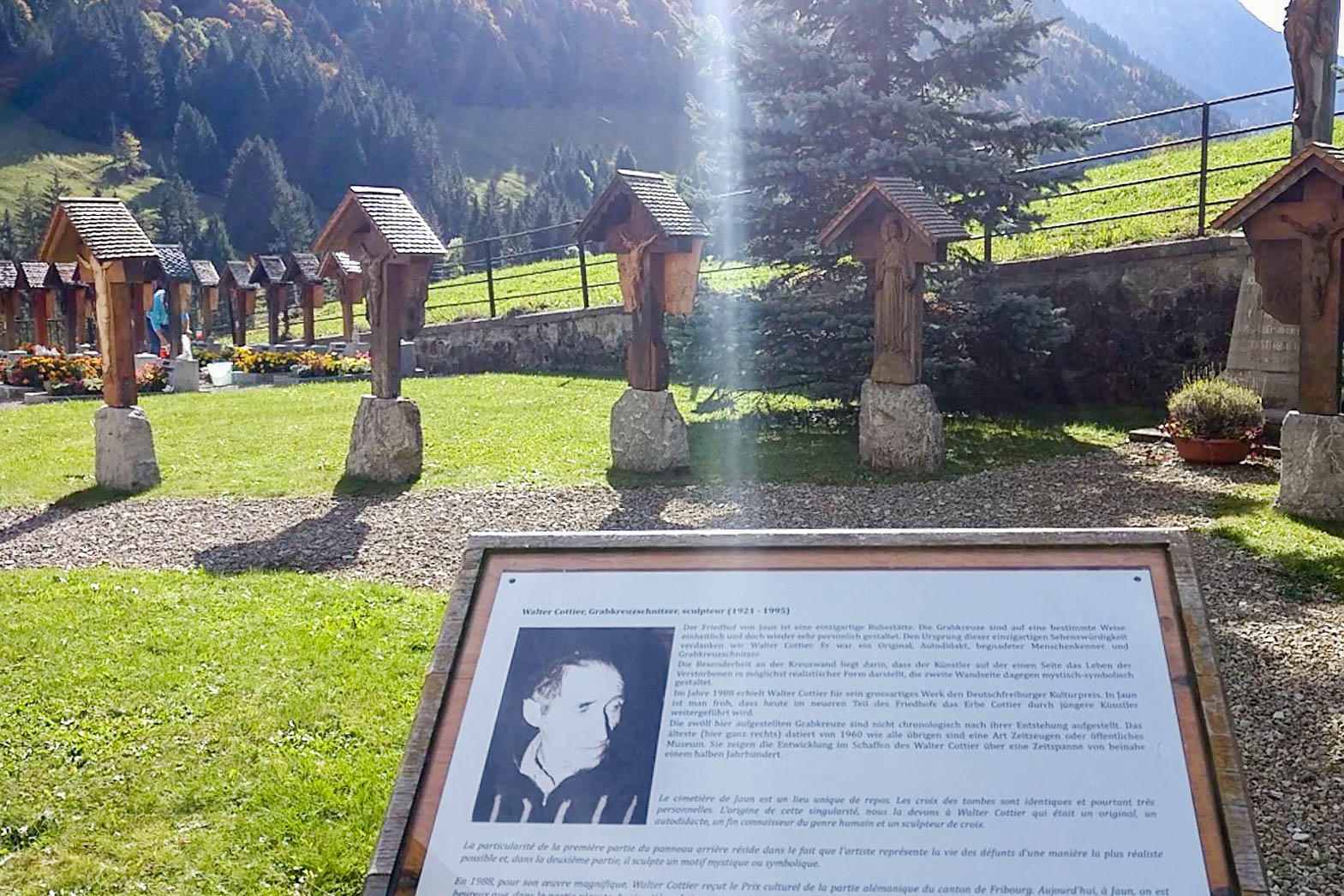 Vier Holzkreuze auf Steinen stehen in einer Reihe auf einem Stück Rasen auf einem Friedhof.