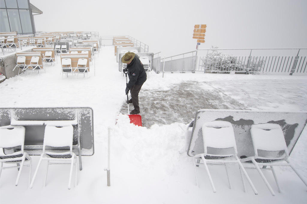رجل يُزيل الثلوج المتراكمة على شرفة مشيدة في أعلى جبل