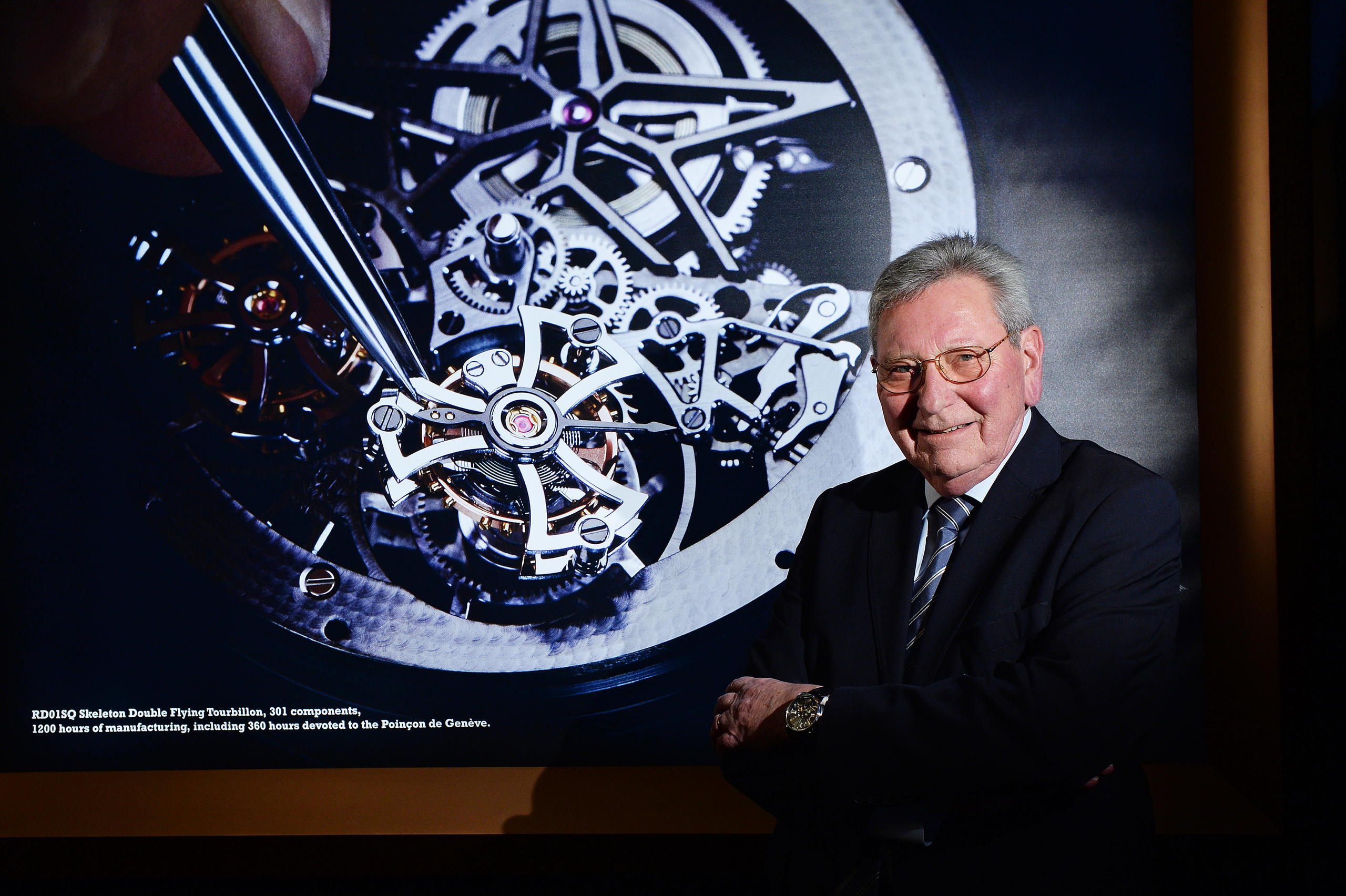 портрет Роже Дюбюи на фоне плаката с часами