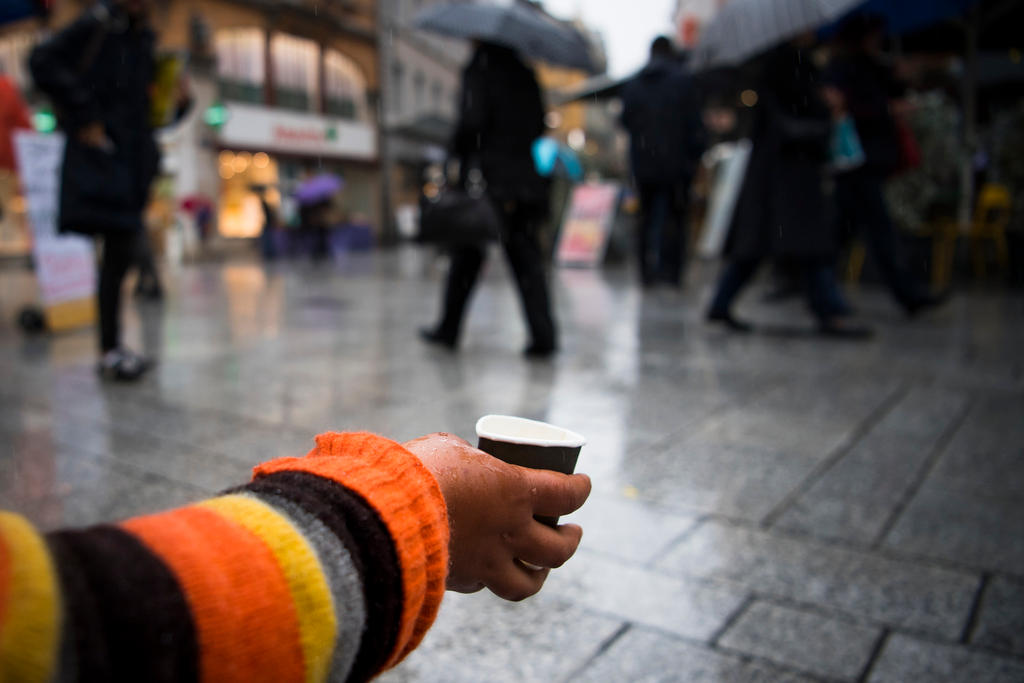 A beggar holds out a hand with a cup for putting money