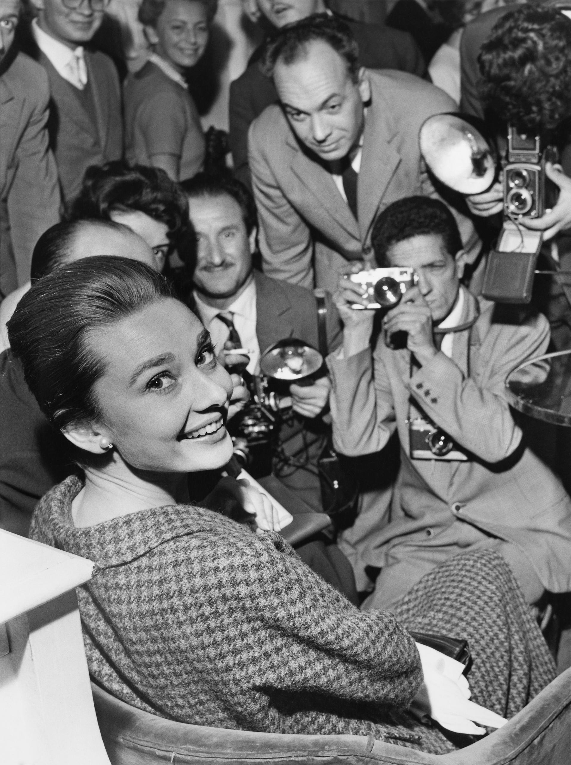 Audrey Hepburn freut sich, von Fotografen und Schaulustigen umzingelt zu sein.