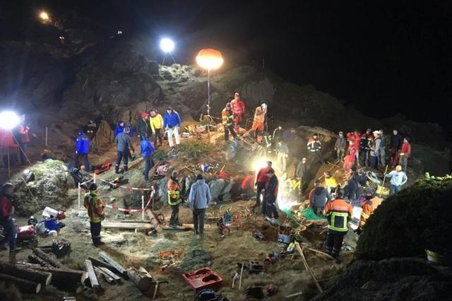 Rescue workers in a rocky area at night under lamplight