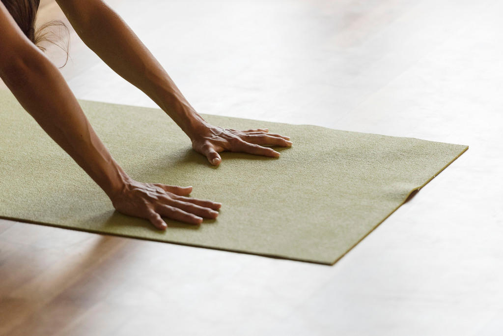Two hands are planted on a green yoga mat