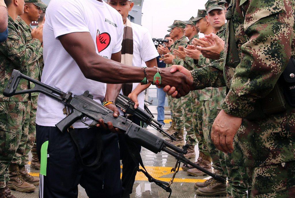A man armed with a gun shakes hands with a line of soldiers