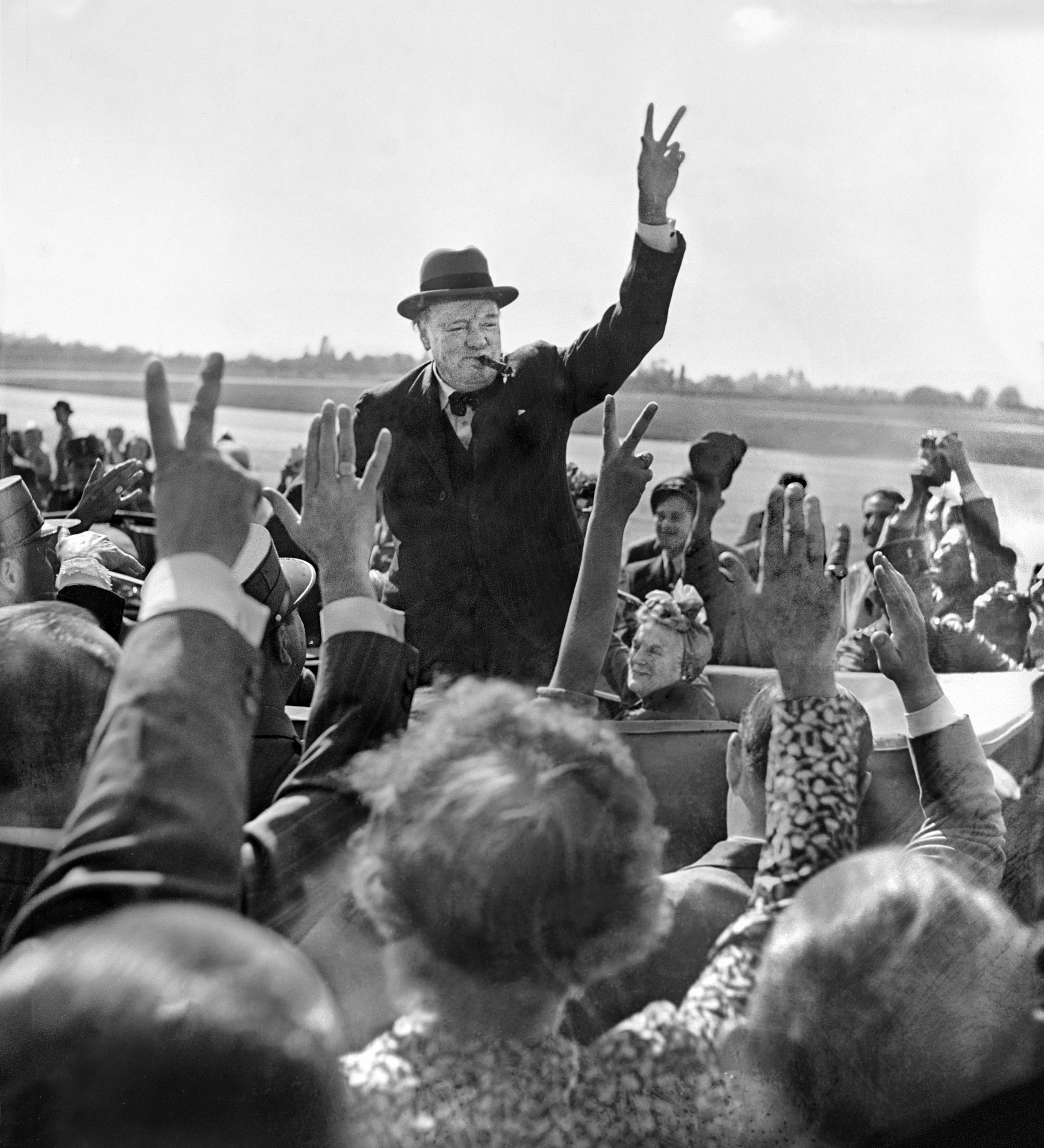 Winston Churchill gives the victory salute to a crowd