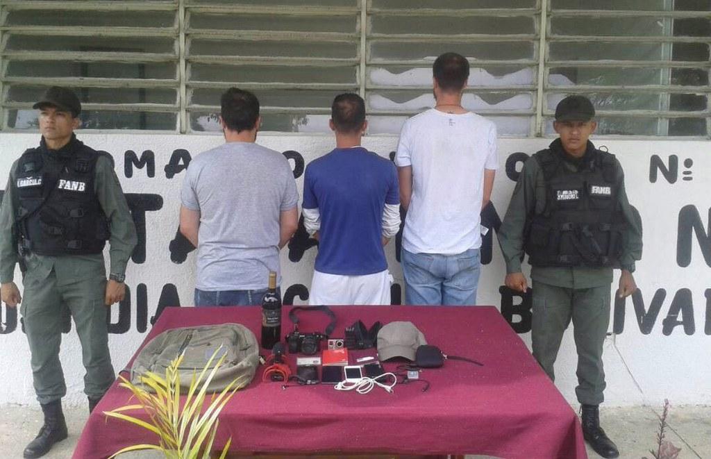 I tre giornalisti, di schiena, insieme a due agenti della Guardia Nacional Bolivariana