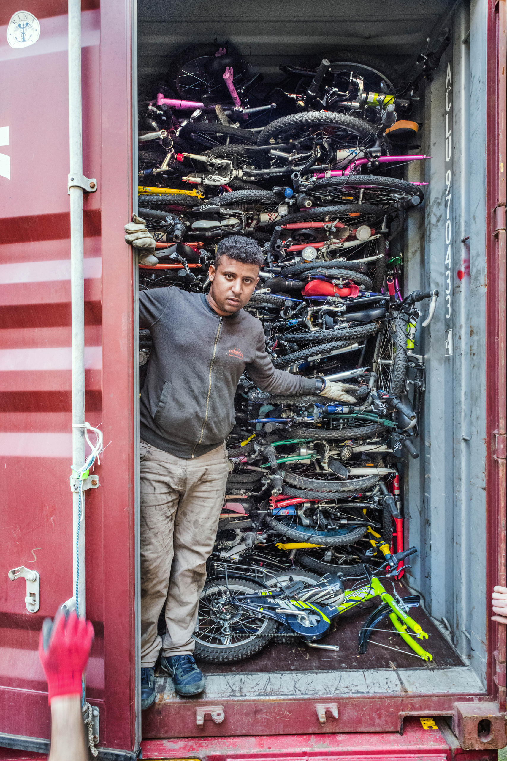 A man peers out of the door of ship container packed with bicycles.