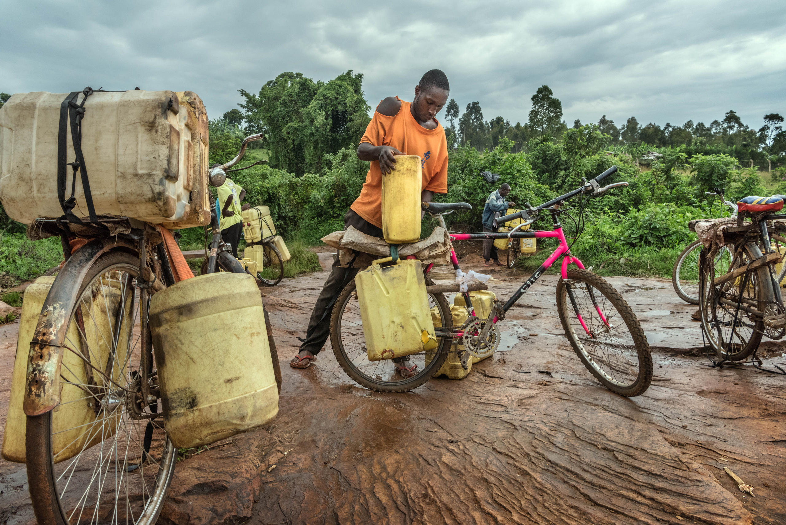 Ernest Mwijage carga su s bidones de agua en su bici para ir a venderlos