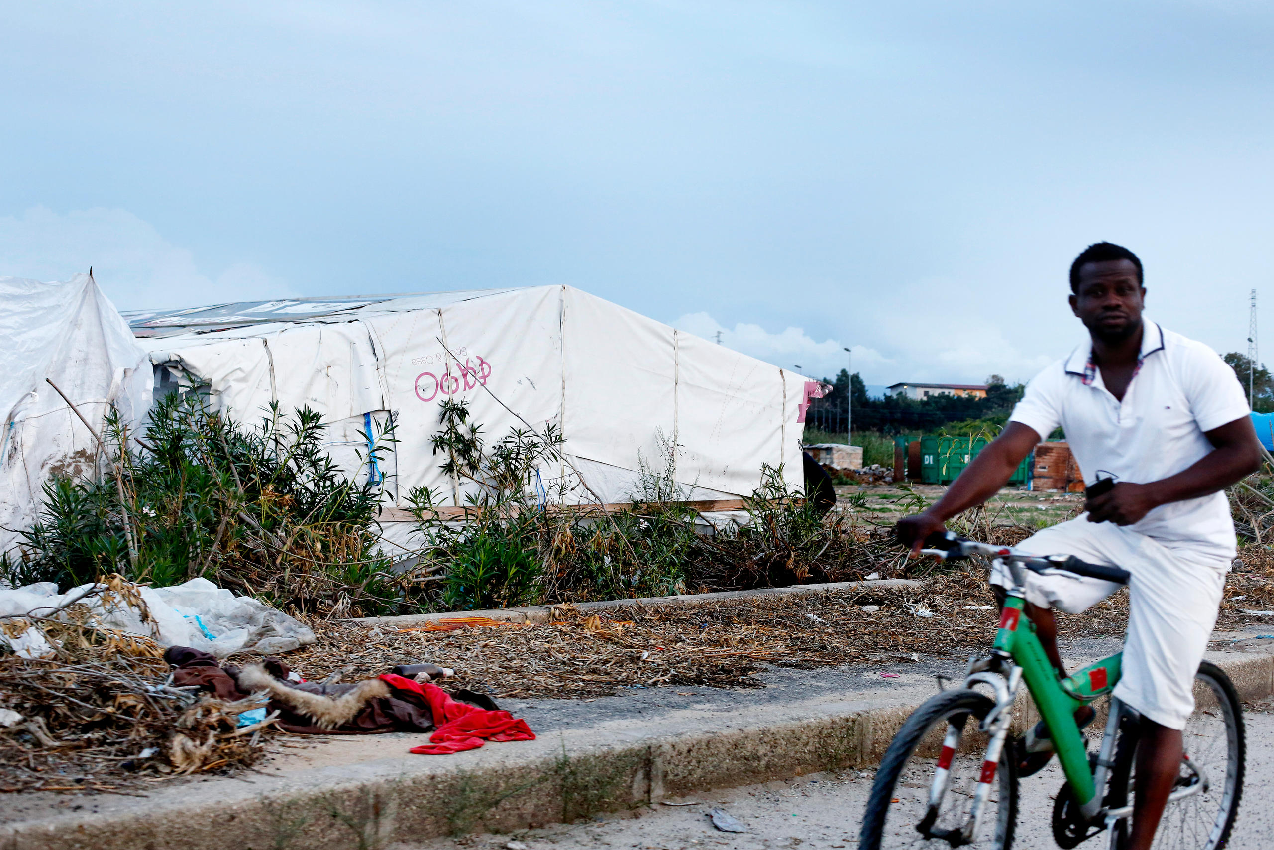 Migrante in bicicletta davanti al campo illegale di San Ferdinando, in Calabria