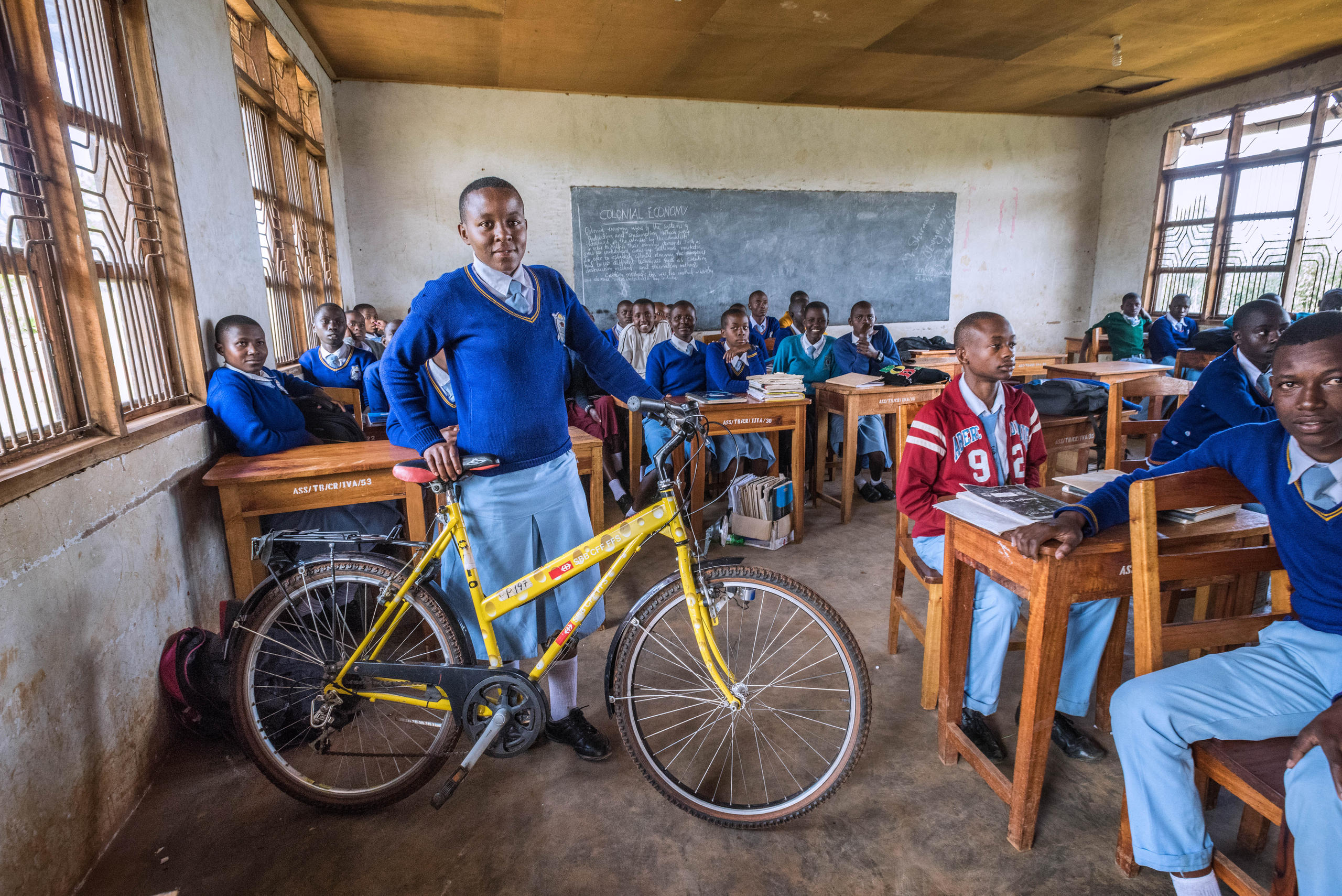 ученица с велосипедом в классной комнате