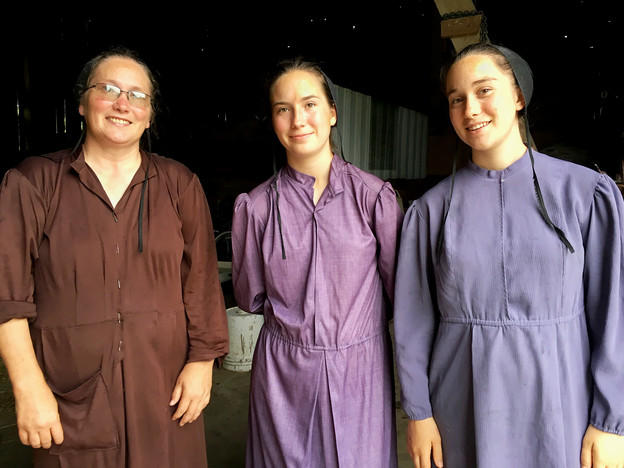 Drei traditionell amisch gekleidete Frauen lächeln in die Kamera