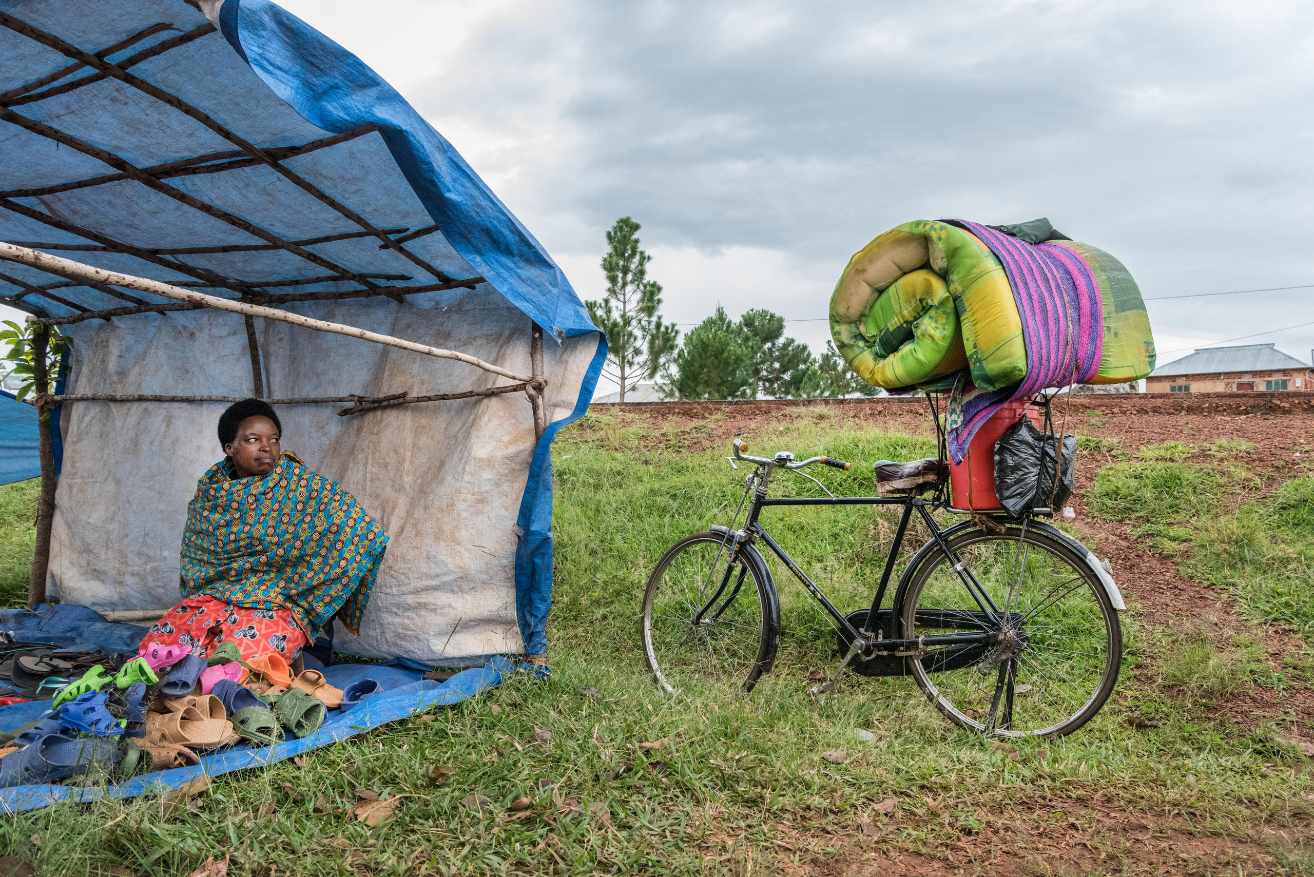 La femme est assise dans une tente, le vélo à côté d elle est chargé.