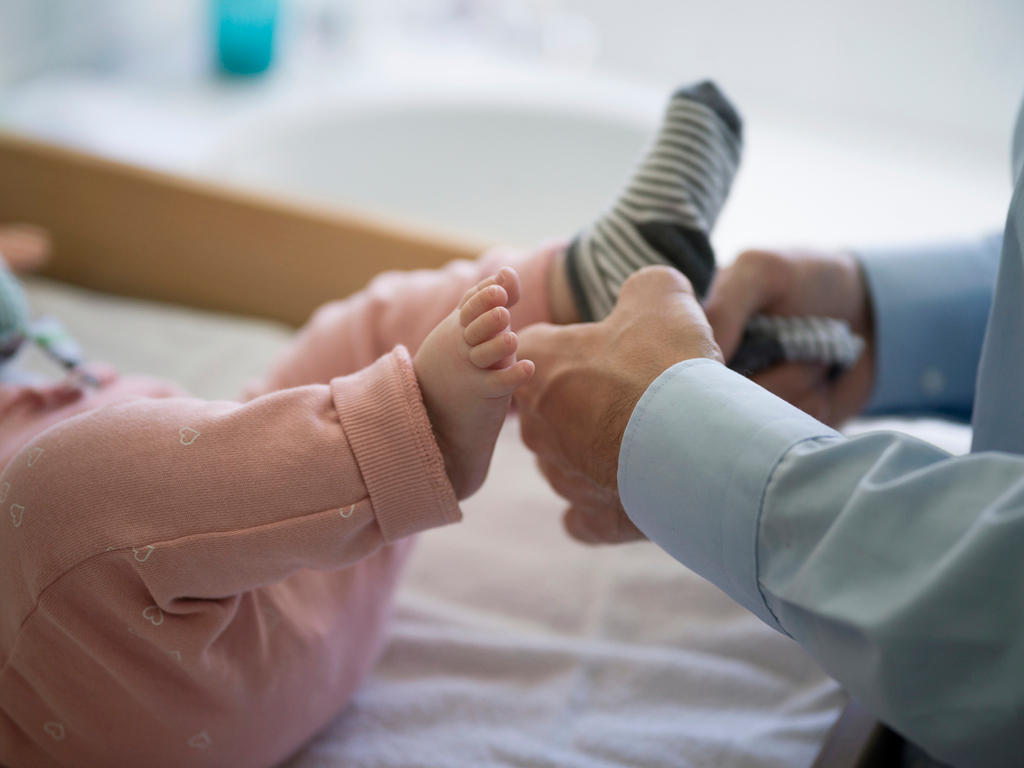 A father puts socks on his five-month-old daughter s feet