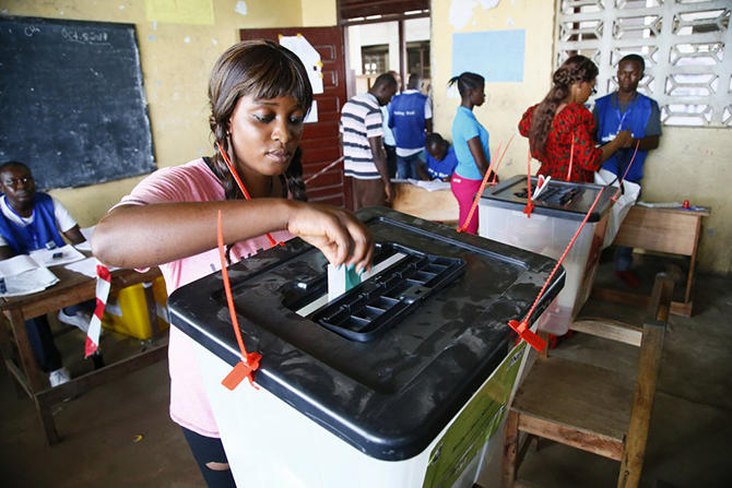 Uma mulher colocando o voto em uma urna eleitoral