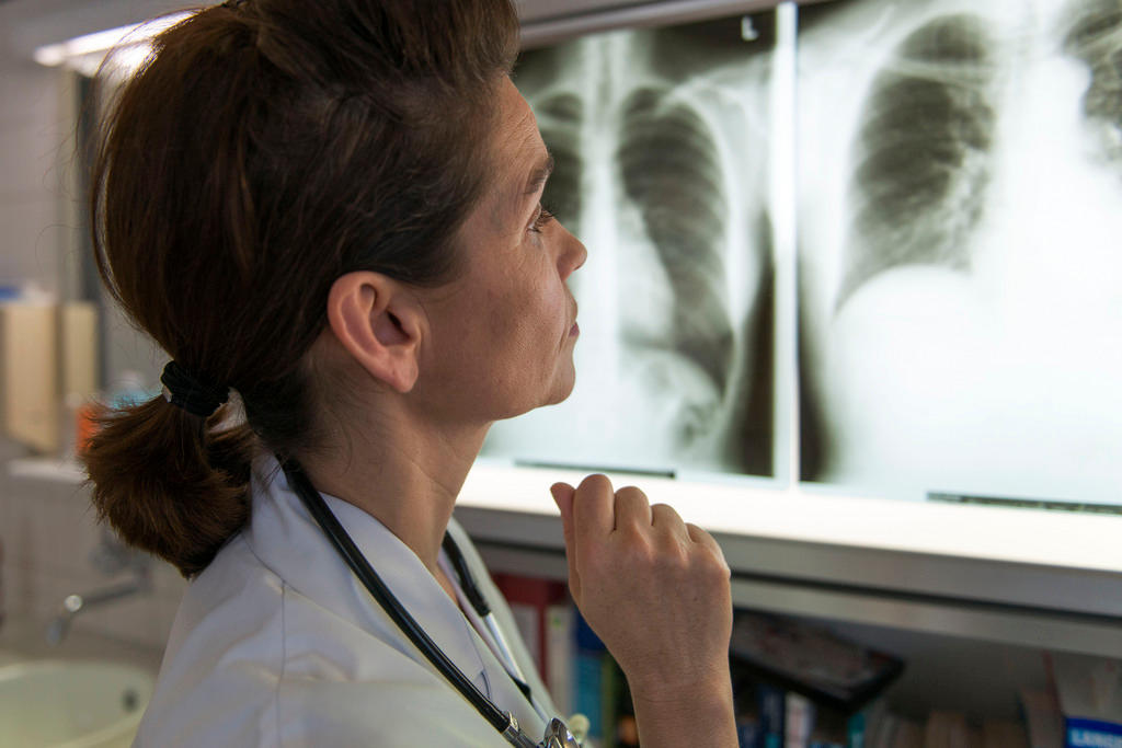 A doctor looks at an X-ray of a torso with her patient 