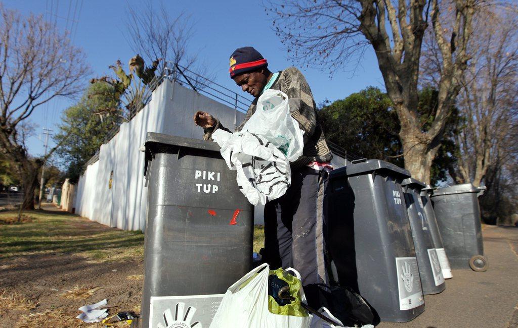 A man looks into a rubbish bin