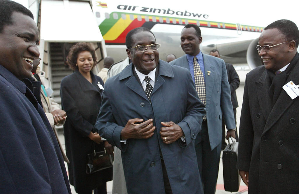 روبرت موغابي يحيط به مسؤولون لدى وصوله إلى مطار جنيف في ديسمبر 2003